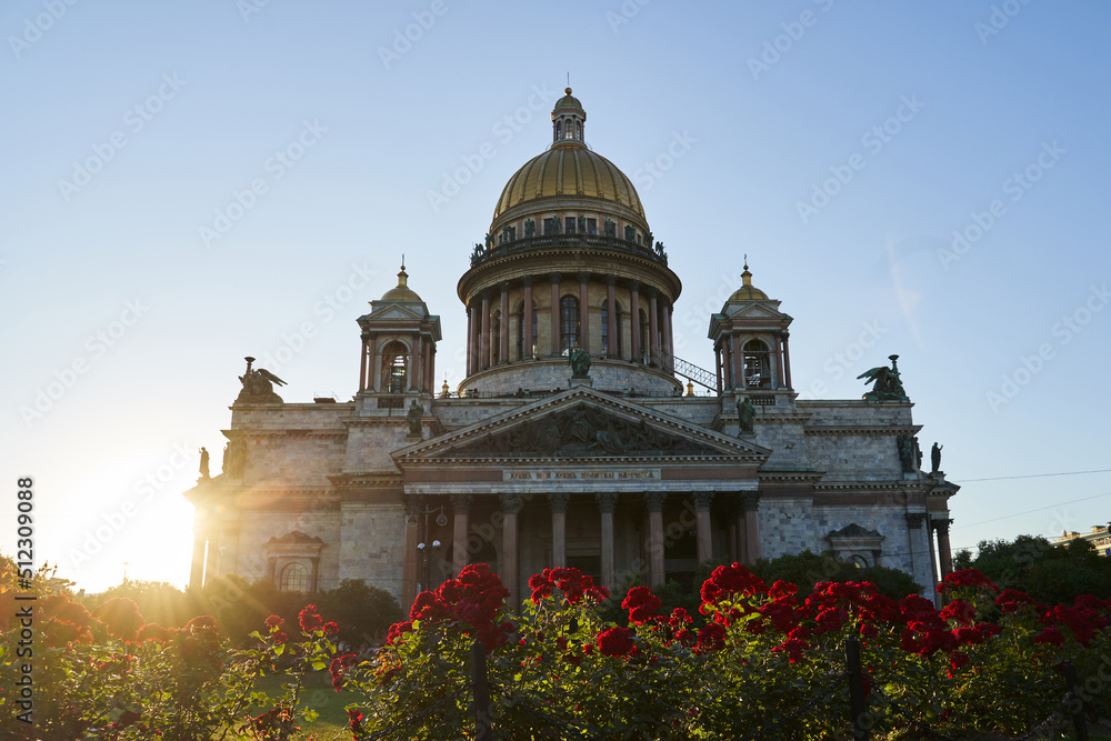 St. Isaac's Cathedral in the sun in the summer and red roses in the flowerbed