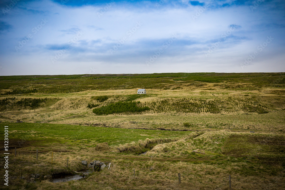 Lone small White House surrounded by a meadow on a hill in Northern Iceland