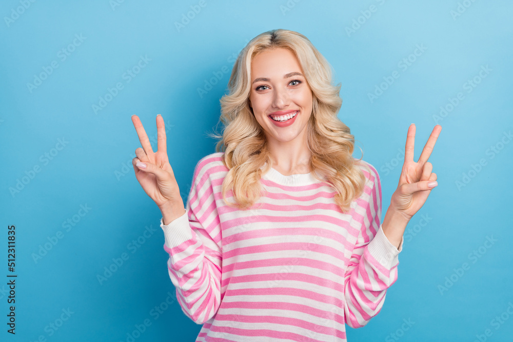 Photo of cool young blond hairdo lady show v-sign wear pink shirt isolated on blue color background Photo of cool young blond hairdo lady show v-sign wear pink shirt isolated on blue color background