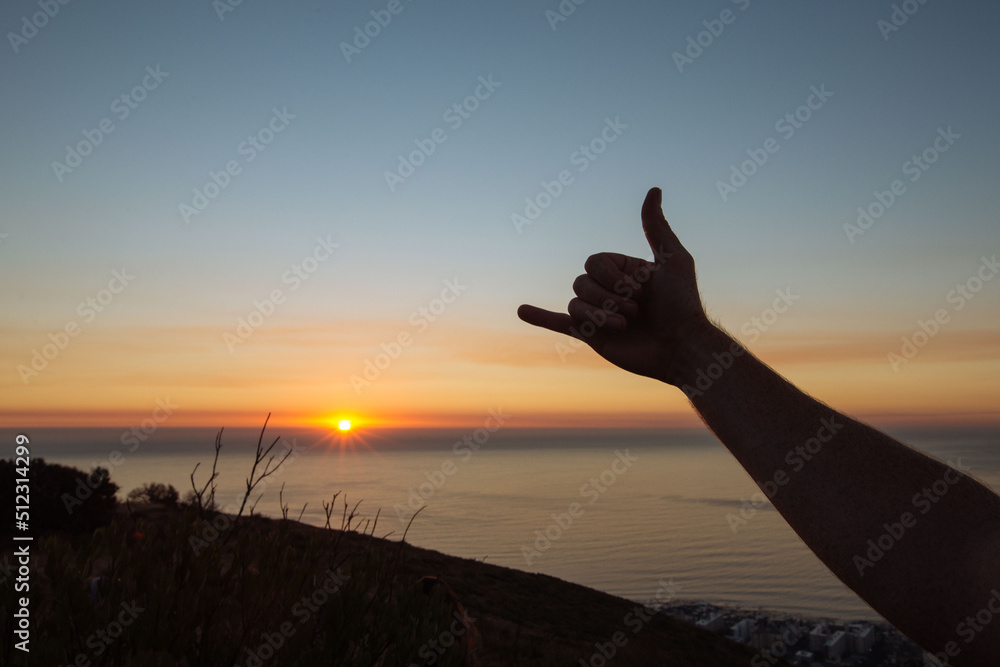 shaka hand sign at sunset on mountain