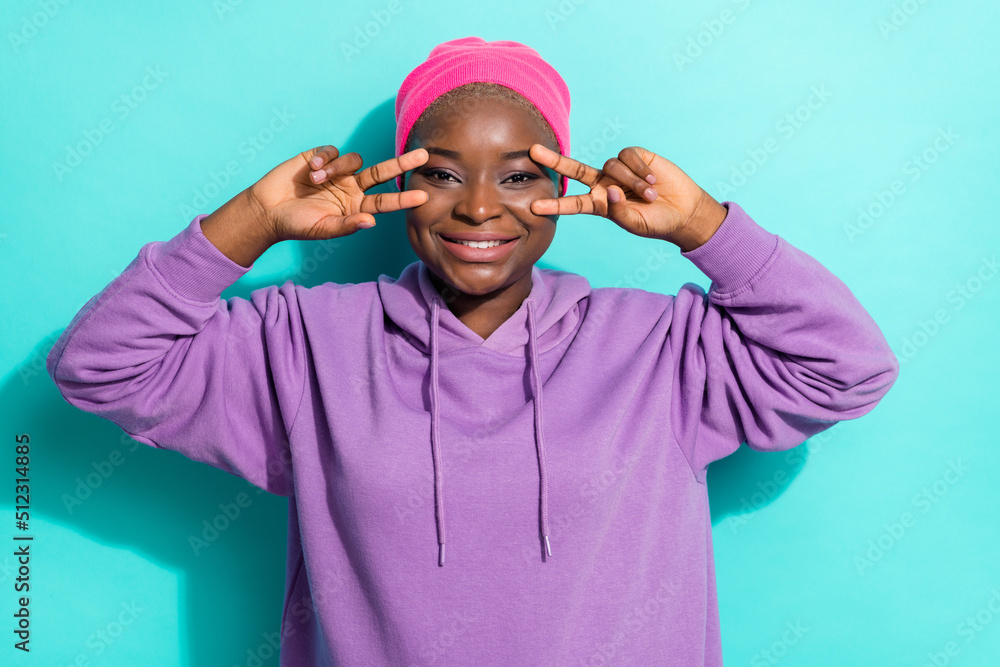 Portrait of attractive cheerful girl showing double v sign near eyes good mood isolated over bright teal turquoise color background Portrait of attractive cheerful girl showing double v sign near eyes good mood isolated over bright teal turquoise color background