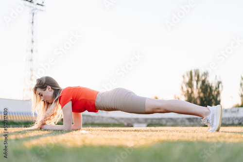 Woman in Red Sports Top Doing Plank with her Belly in. Exercises for Pumping Abdominal Muscles