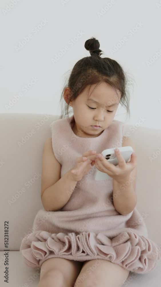 Portrait of a cute attractive charming sweet calm peaceful focused Asian girl using the 5g online internet application in a light white interior of the living room of the house indoors, vertical video Portrait of a cute attractive charming sweet calm peaceful focused Asian girl using the 5g online internet application in a light white interior of the living room of the house indoors, vertical video