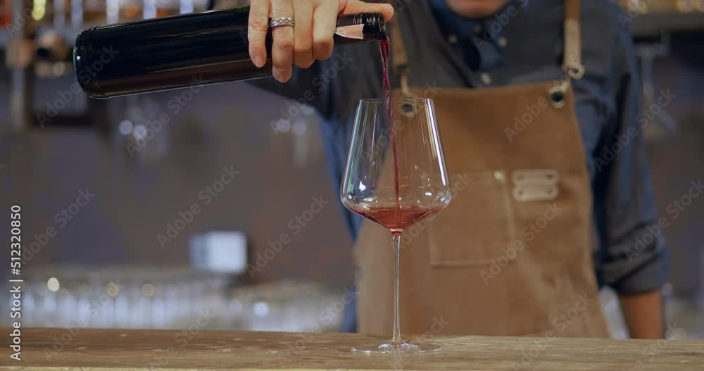 Young Asian sommelier pouring wine into glasses to serve customers at the bar. A bartender wearing glasses and a hair tie Wine stands serving drinks at the hotel bar. Young Asian sommelier pouring wine into glasses to serve customers at the bar. A bartender wearing glasses and a hair tie Wine stands serving drinks at the hotel bar.