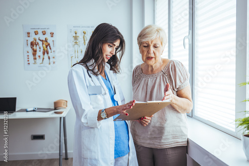 Charming female doctor giving advice to a senior female patient. Mature woman visiting doctor in clinic. Smiling female doctor in consultation with senior patient.