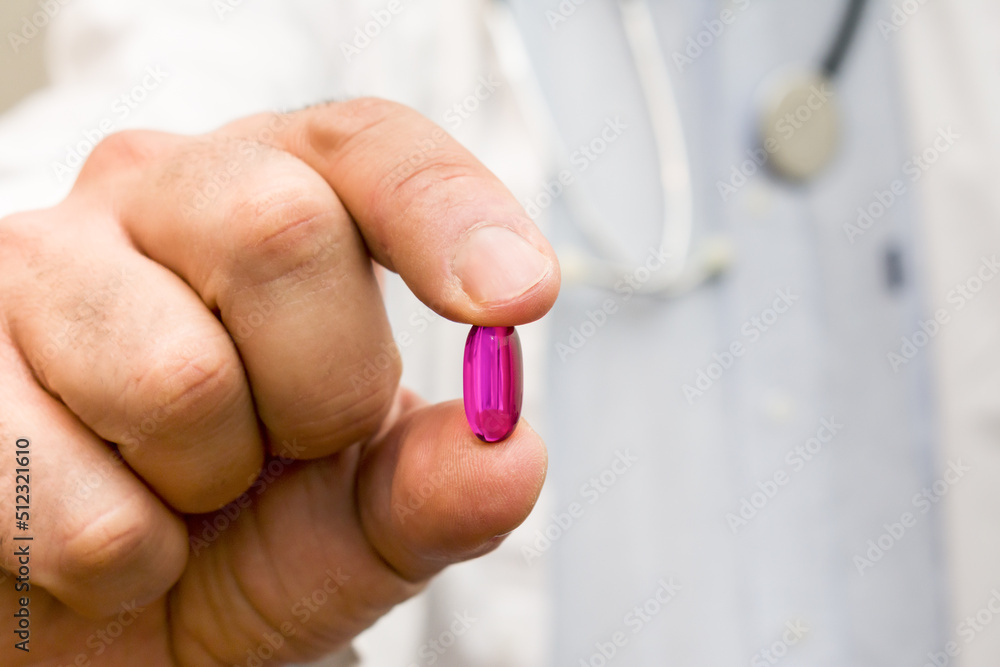 Close up of mature male doctor holding red pill