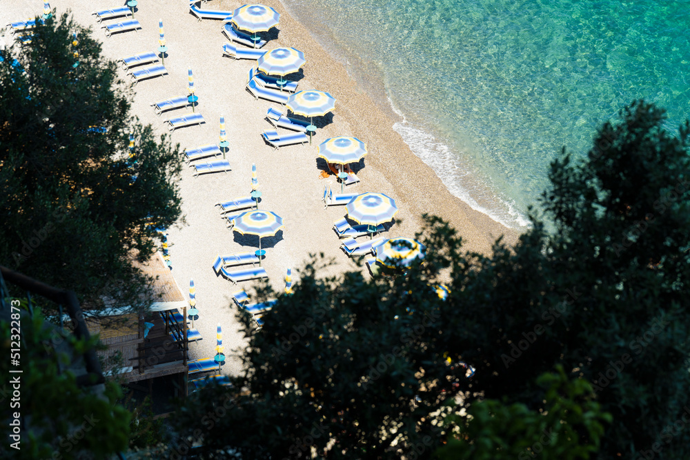 View from above, stunning aerial view of some beach umbrellas on a beautiful beach bathed by a crystal clear water. Amalfi Coast, Italy.