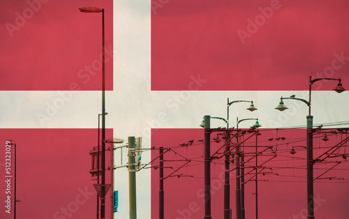 Denmark flag with tram connecting on electric line with blue sky as background, electric railway train and power supply lines, cables connections and metal pole overhead catenary wire