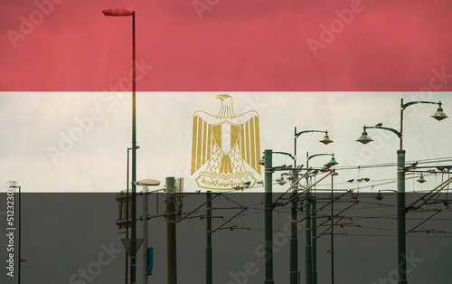 Egypt flag with tram connecting on electric line with blue sky as background, electric railway train and power supply lines, cables connections and metal pole overhead catenary wire
