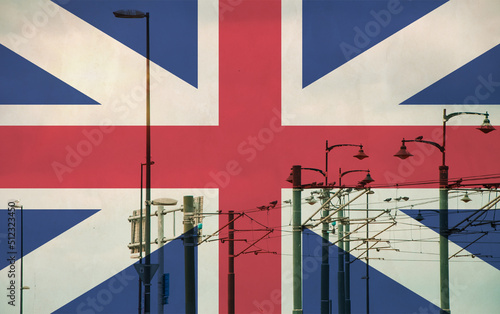 Great Britain, England flag with tram connecting on electric line with blue sky as background, electric railway train and power supply lines, cables connections and metal pole overhead catenary wire