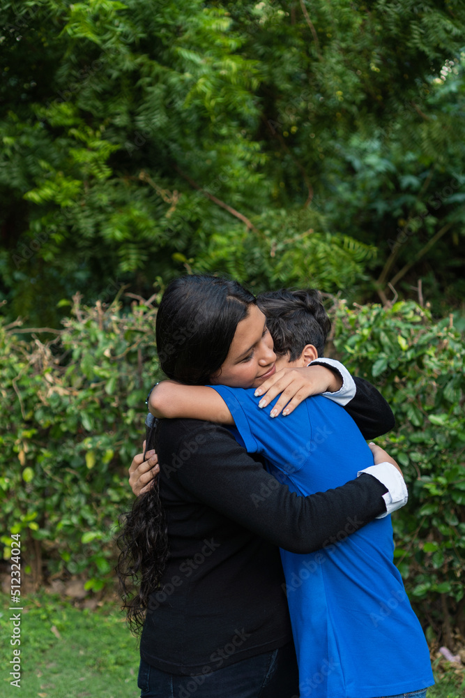 Two happy siblings laughing and hugging in a park Two happy siblings laughing and hugging in a park