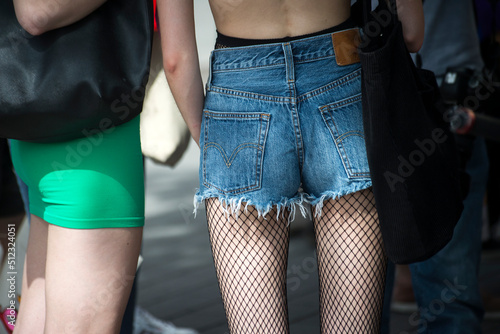 Closeup of young woman wearing a mini jeans short and sexy tights standing in the street photo