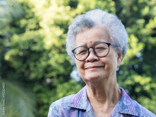Senior woman with short gray hair looking at the camera with a smile while standing in the garden