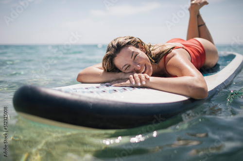 Low angle view of smiling woman lying down on paddle board photo