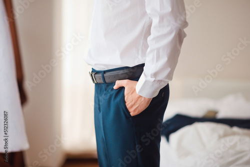 Close-up photo of a men's leather belt and hands in his pocket. Stylish business look. Men's clothing accessories.