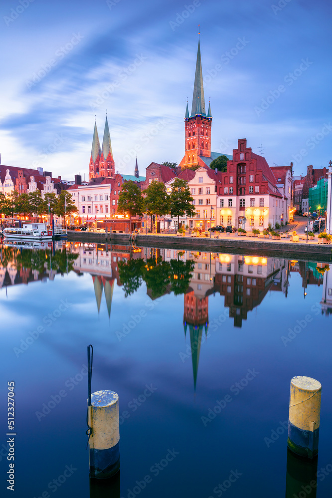 Lubeck, Germany. Cityscape image of riverside Lubeck with reflection of the city in Trave River at sunset.