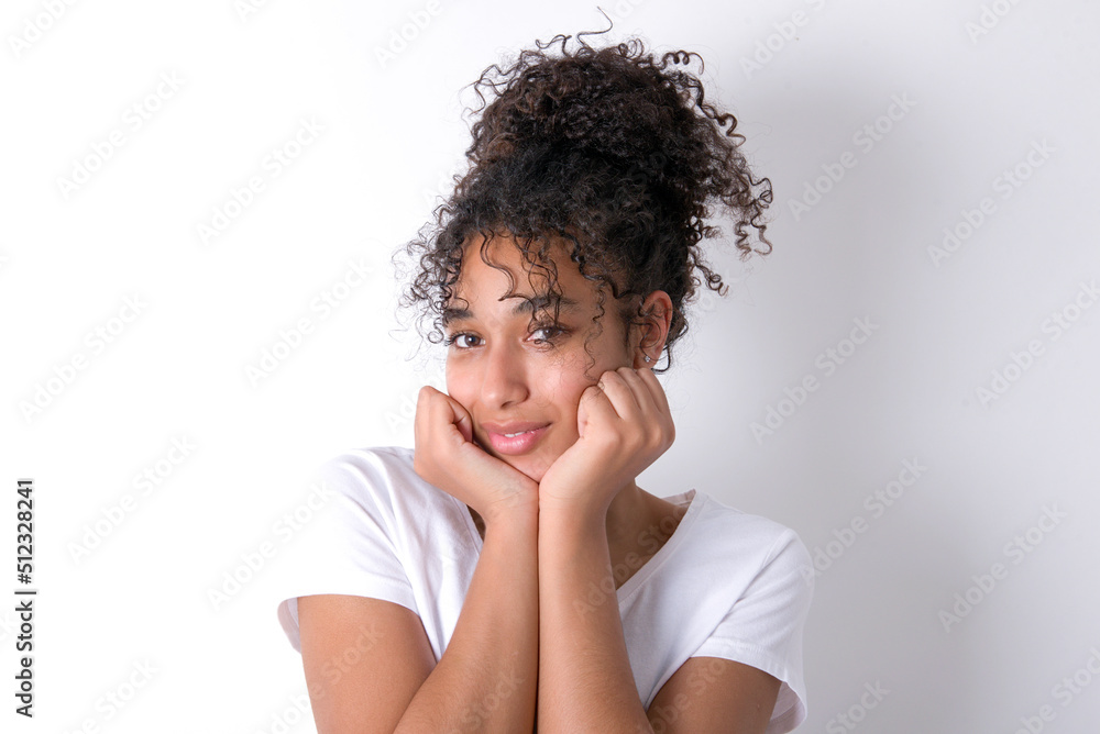 Portrait of sad Young beautiful girl with afro hairstyle wearing white t-shirt over white background hands face Portrait of sad Young beautiful girl with afro hairstyle wearing white t-shirt over white background hands face