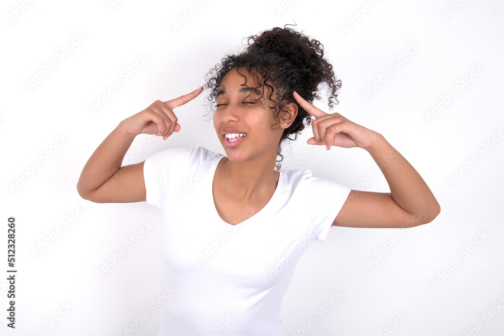 Photo of crazy Young beautiful girl with afro hairstyle wearing white t-shirt over white background screaming and pointing with fingers at hair closed eyes Photo of crazy Young beautiful girl with afro hairstyle wearing white t-shirt over white background screaming and pointing with fingers at hair closed eyes