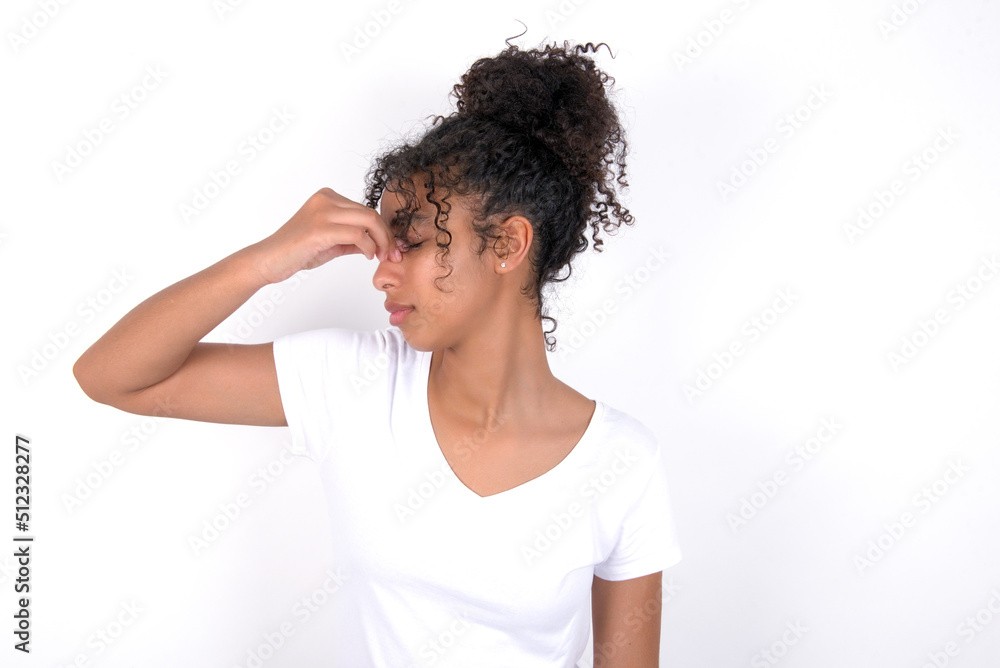 Sad Young beautiful girl with afro hairstyle wearing white t-shirt over white background suffering from headache holding hand on her face Sad Young beautiful girl with afro hairstyle wearing white t-shirt over white background suffering from headache holding hand on her face