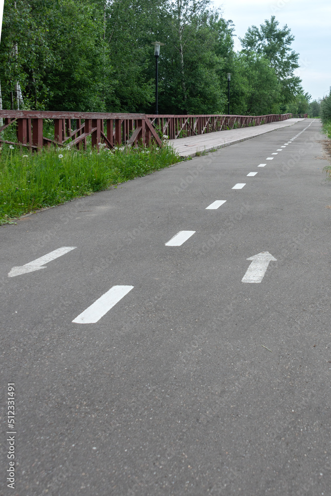 Obraz premium Asphalt bike path parallel to the eco-trail in the public park.
