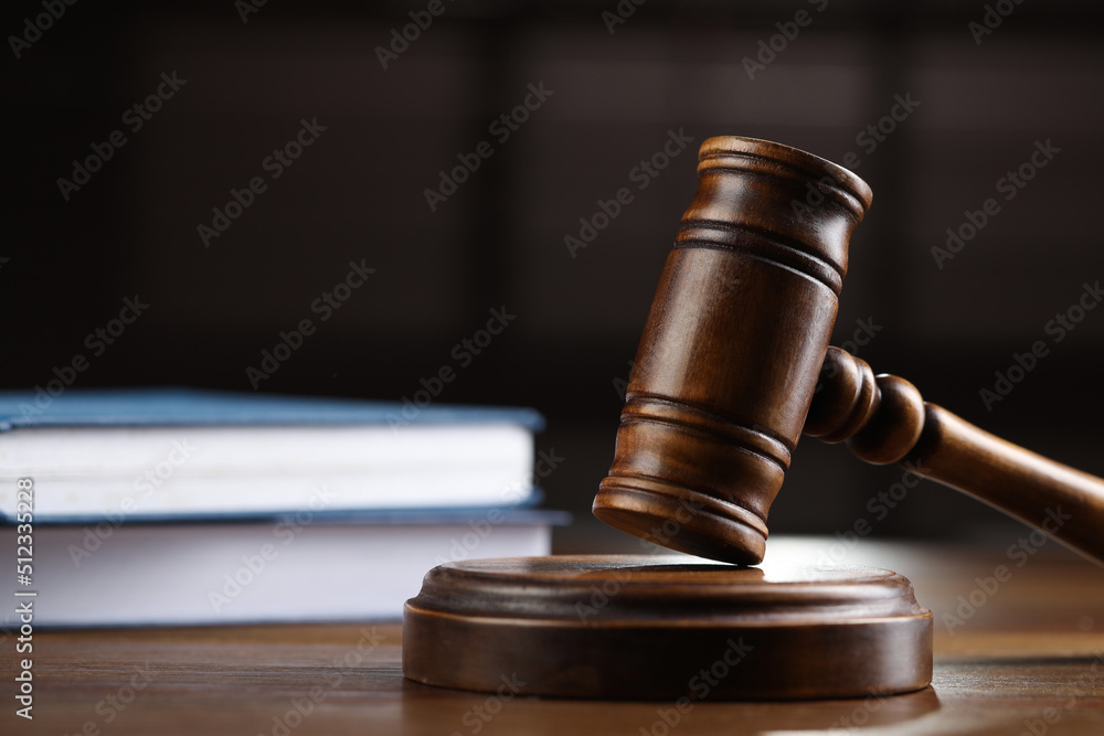 Wooden gavel and books on table against blurred background, closeup Wooden gavel and books on table against blurred background, closeup