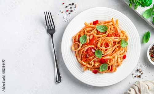Classic linguini pasta with tomatoes on a light gray background. Top view, space to copy.