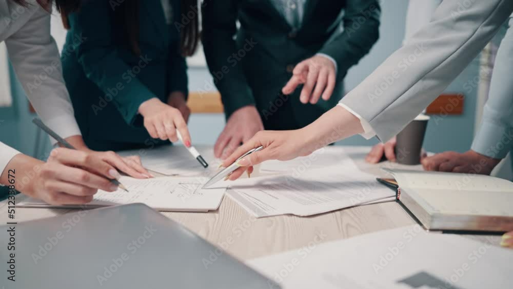 A team of business people are discussing the project together in the office. Close-up of hands and documents on a desk. A team of business people are discussing the project together in the office. Close-up of hands and documents on a desk.