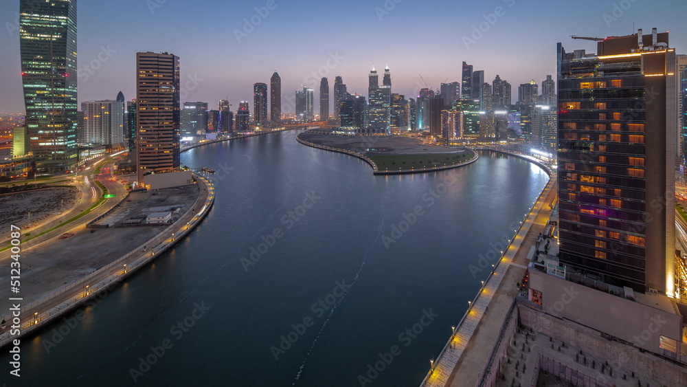 Fototapeta premium Cityscape of skyscrapers in Dubai Business Bay with water canal aerial day to night timelapse