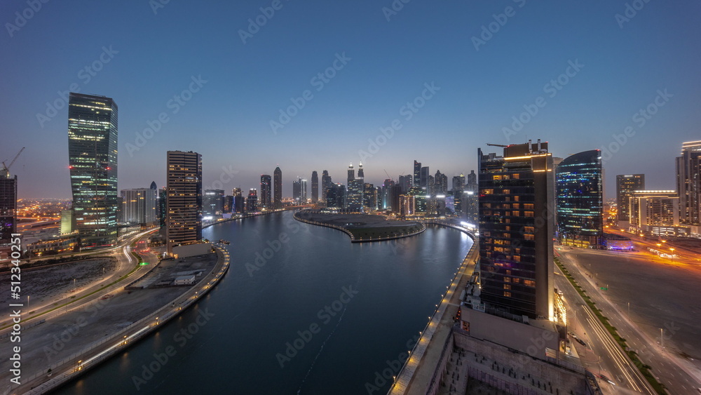 Fototapeta premium Cityscape of skyscrapers in Dubai Business Bay with water canal aerial day to night timelapse