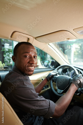 Portrait of smiling personal driver in gray shirt driving to client