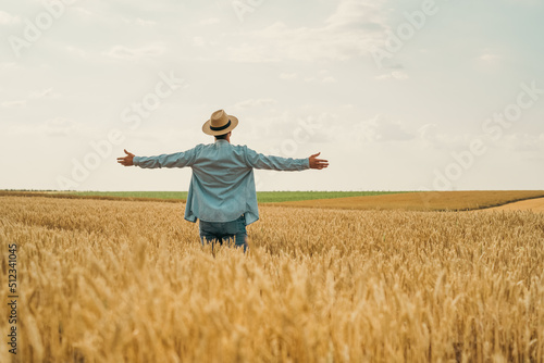 Happy farmer with arms outstretched standing in his growing wheat field.  © inesbazdar