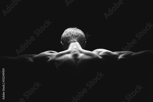 Handsome power athletic man in dramatic light. Strong bodybuilder with perfect shoulders, biceps, triceps, back, delta and chest. Strength and motivation. Bottom view