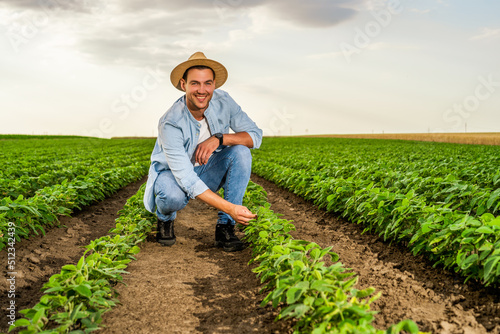 Happy farmer spending time in his growing  soybean field.