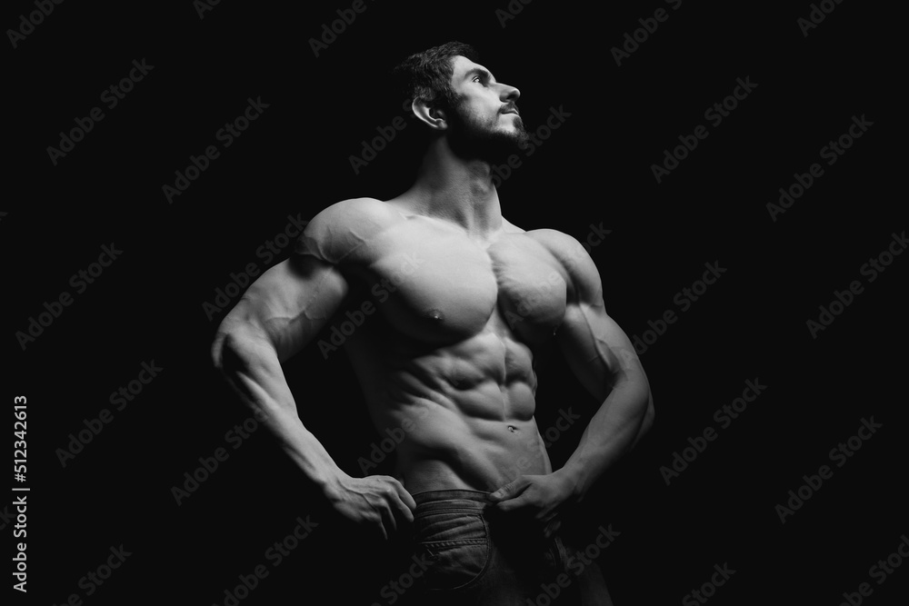 Portrait of shirtless muscular man in a jeans. Young male hunk showing his perfect body and muscles on black background Portrait of shirtless muscular man in a jeans. Young male hunk showing his perfect body and muscles on black background