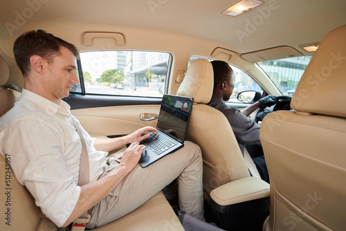 Young entrepreneur working on laptop when riding taxi to office