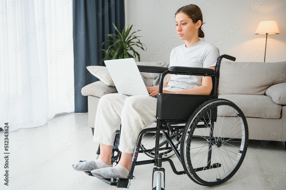 woman in a wheelchair works on the laptop PC in the home office with an assistance dog as a companion woman in a wheelchair works on the laptop PC in the home office with an assistance dog as a companion