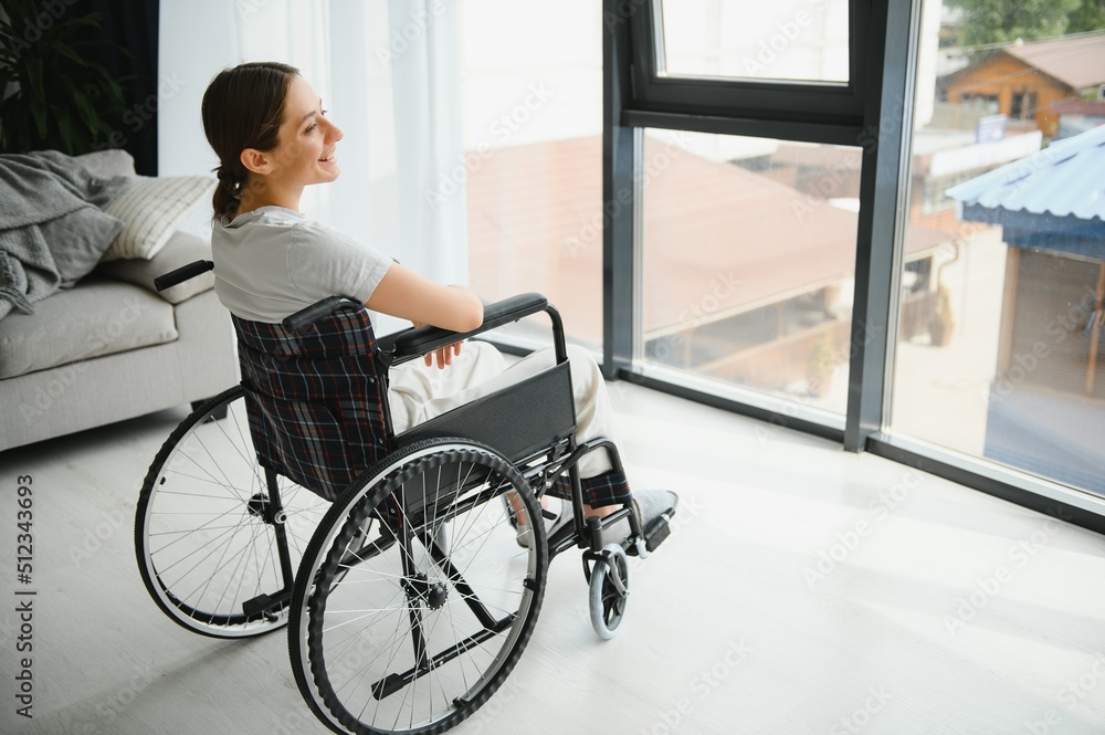 woman looking away while sitting in wheelchair at home woman looking away while sitting in wheelchair at home
