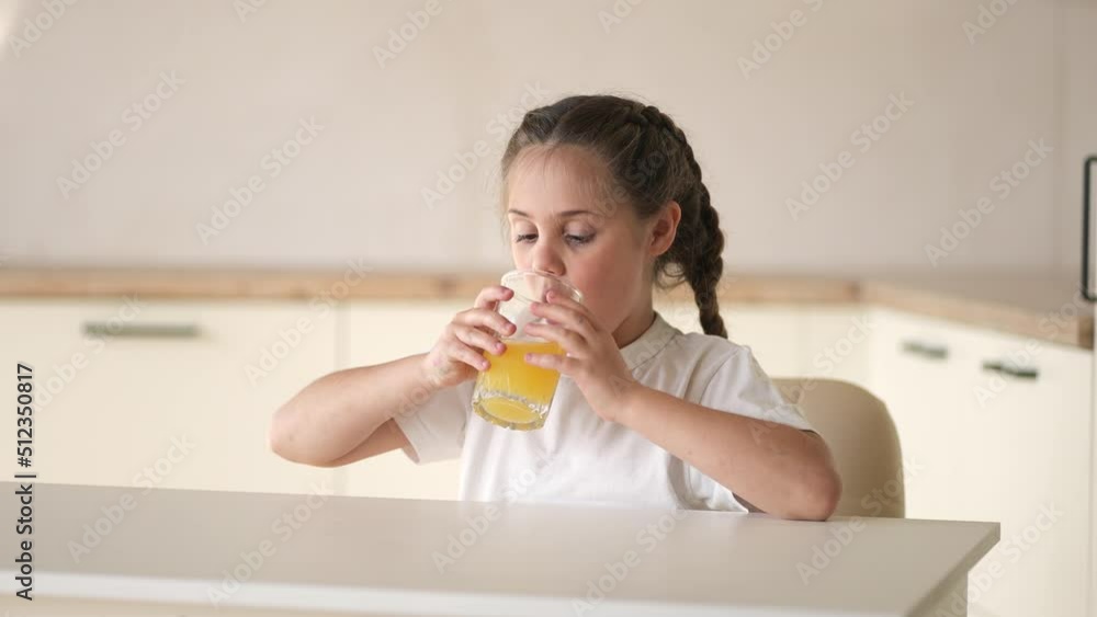 girl child drinking juice. happy family a healthy eating kid dream concept. daughter girl drinking yellow indoors juice from a glass cup in the kitchen. child drinking fruit juice girl child drinking juice. happy family a healthy eating kid dream concept. daughter girl drinking yellow indoors juice from a glass cup in the kitchen. child drinking fruit juice