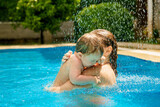 Summer outdoor fun in the pool in the villa. Family happiness. Mom and daughter in the pool. Happy child is having fun. A woman teaches a baby to float on the water and swim