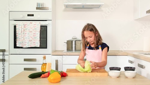 Cute girl cutting ice berg lettuce in modern kitchen.