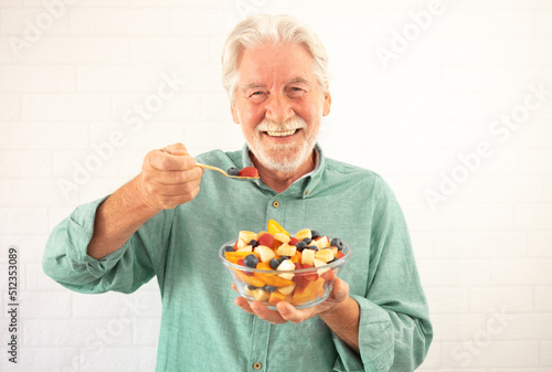 Portrait of smiling senior white-haired man ready to eat a salad of fresh summer fruits. Breakfast or lunch time, healthy eating photo