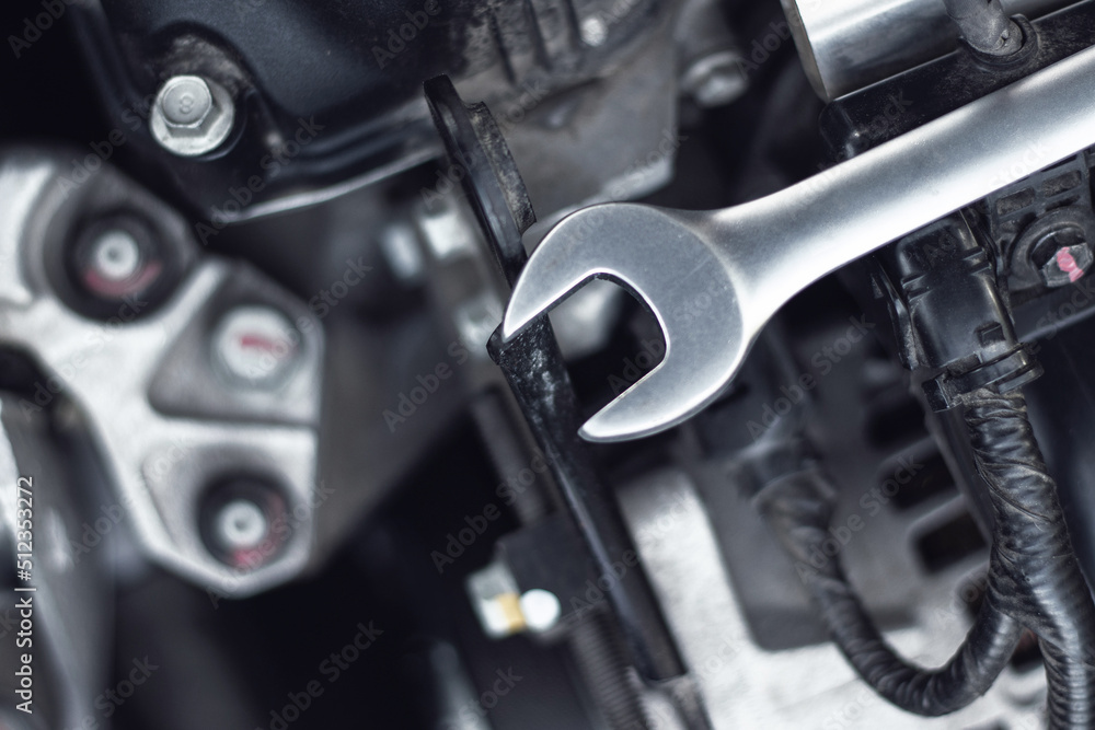 The wrench lies on the car engine in the engine compartment.
