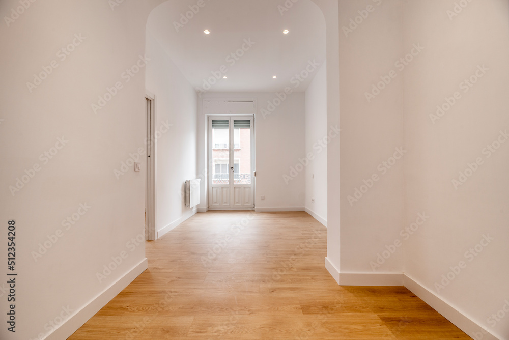 Empty room with oak parquet flooring and woodwork on doors and balcony, basket-handle arch separating rooms and light oak flooring Empty room with oak parquet flooring and woodwork on doors and balcony, basket-handle arch separating rooms and light oak flooring