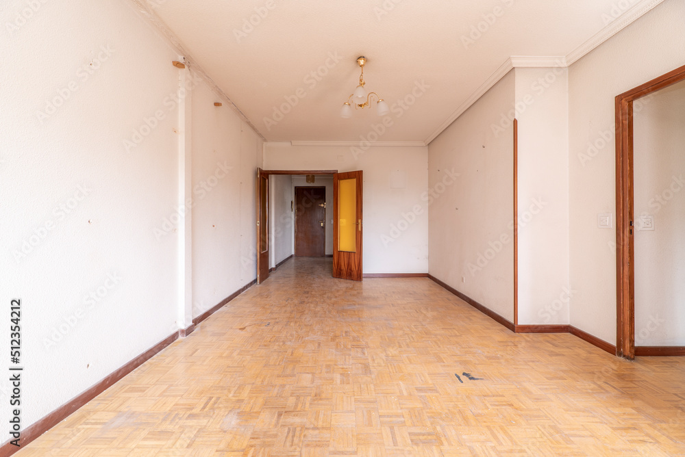 Empty room with parquet floors in need of a coat of varnish, wood carpentry and orange glass on the doors Empty room with parquet floors in need of a coat of varnish, wood carpentry and orange glass on the doors