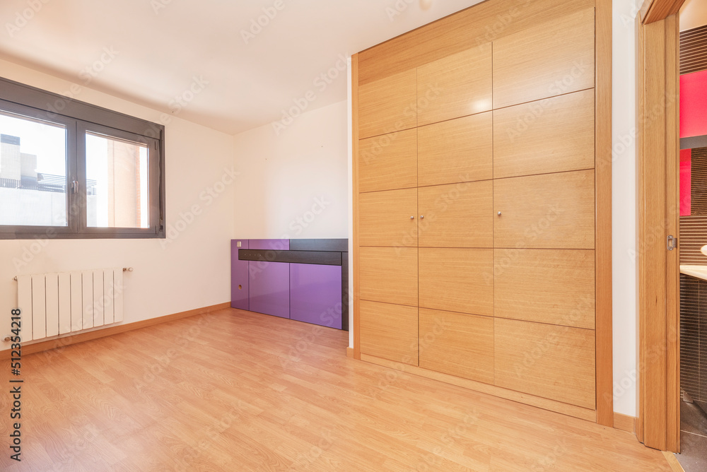 Obraz premium Empty living room with wooden floor, white painted walls, brown aluminum window and built-in wardrobe with oak wood doors