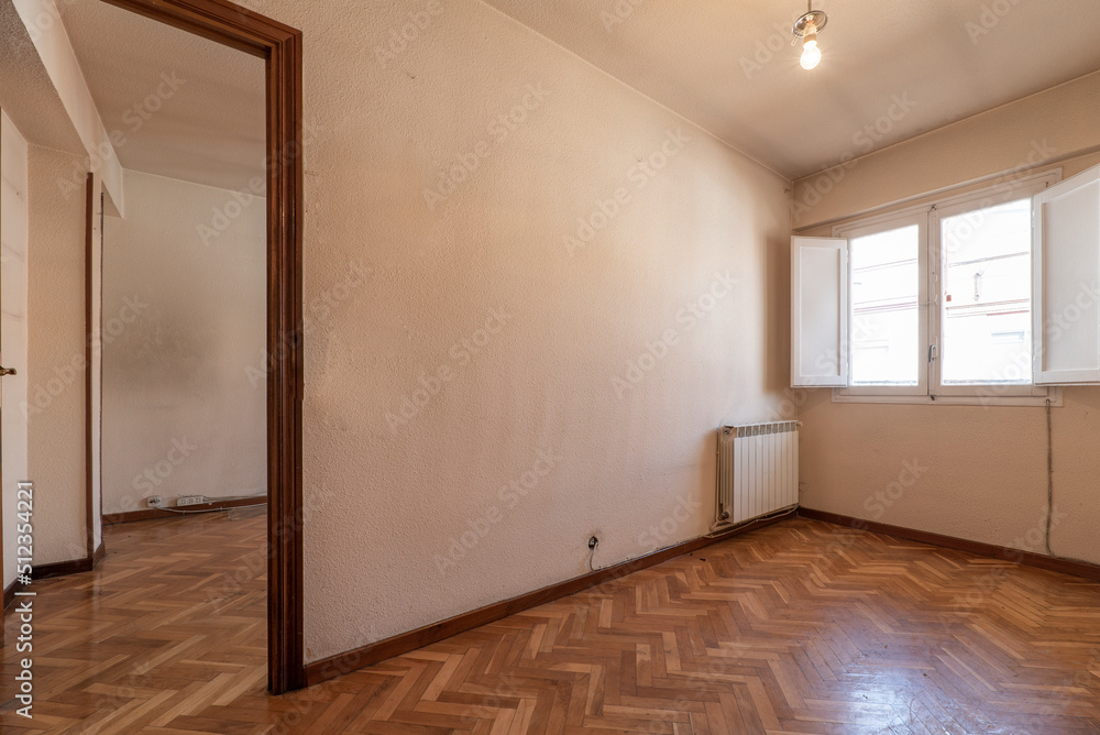 Empty room with bright oak parquet floor, white painted walls and reddish woodwork on white wooden doors and windows with shutters Empty room with bright oak parquet floor, white painted walls and reddish woodwork on white wooden doors and windows with shutters