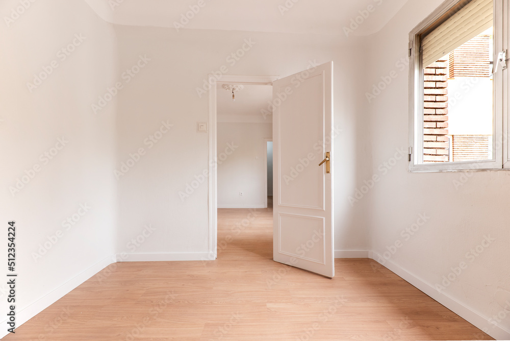 Empty living room with white painted walls with aluminum window, white woodwork and light oak flooring Empty living room with white painted walls with aluminum window, white woodwork and light oak flooring