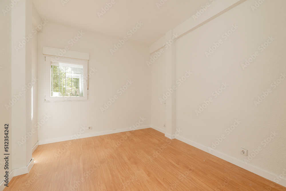 Empty room with oak parquet floor, white painted walls and aluminum windows overlooking a park Empty room with oak parquet floor, white painted walls and aluminum windows overlooking a park