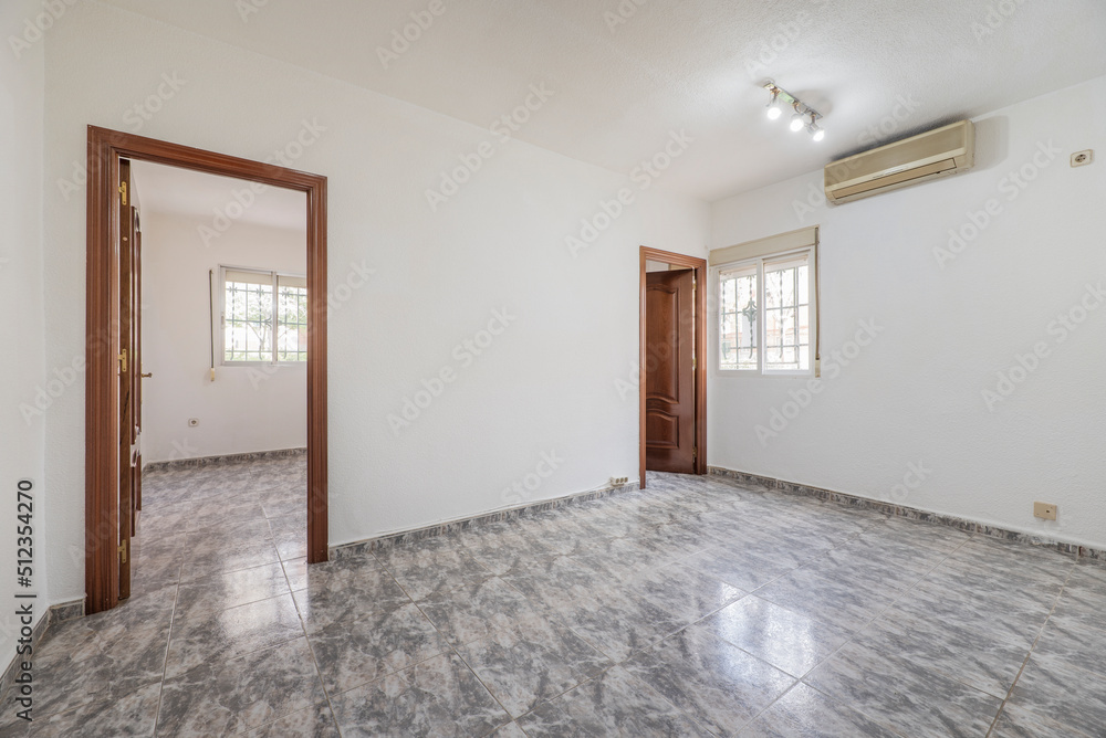 Empty room with plain white painted walls, access doors to two rooms and grayish ceramic stoneware floors Empty room with plain white painted walls, access doors to two rooms and grayish ceramic stoneware floors