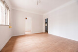 Empty room with oak parquet floor, white painted walls and white woodwork and plaster moldings on the ceiling
